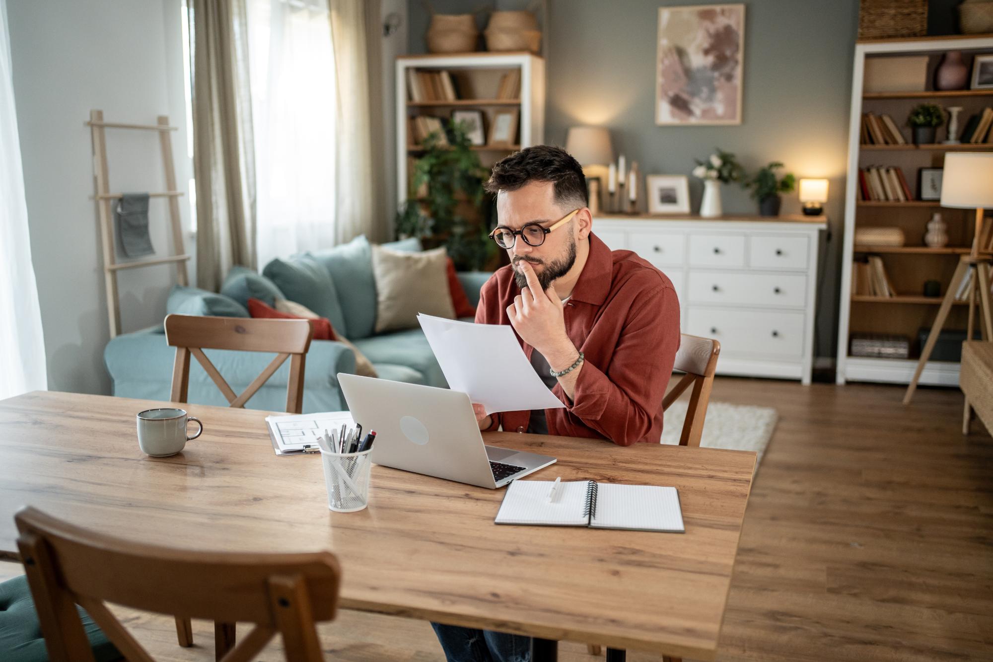 homme réflechit, homme chez lui, homme avec une feuille à la main