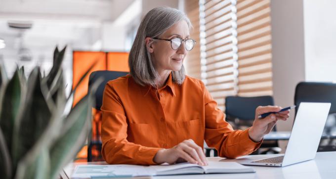 Femme avec cahier devant ordinateur