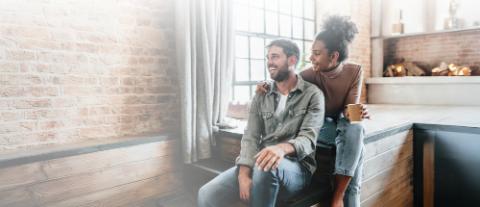 couple souriant devant une fenêtre