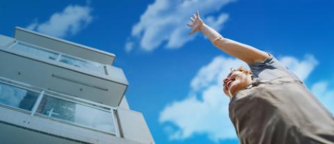 Femme levant le bras vers le ciel devant un immeuble