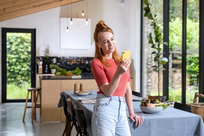 une jeune femme avec son smartphone dans la cuisine