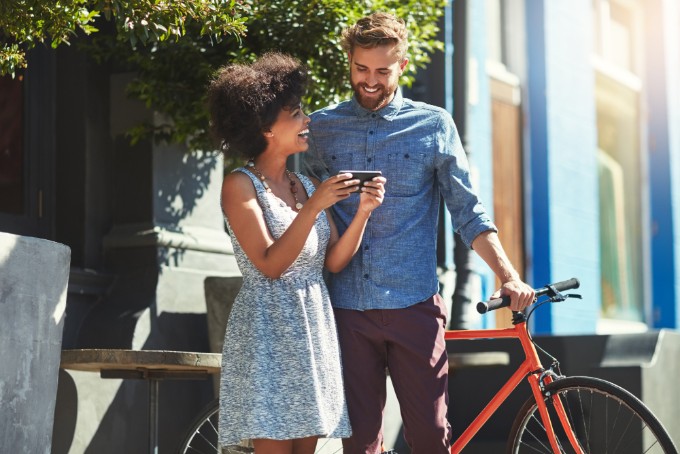 2 personnes souriant devant un smartphone