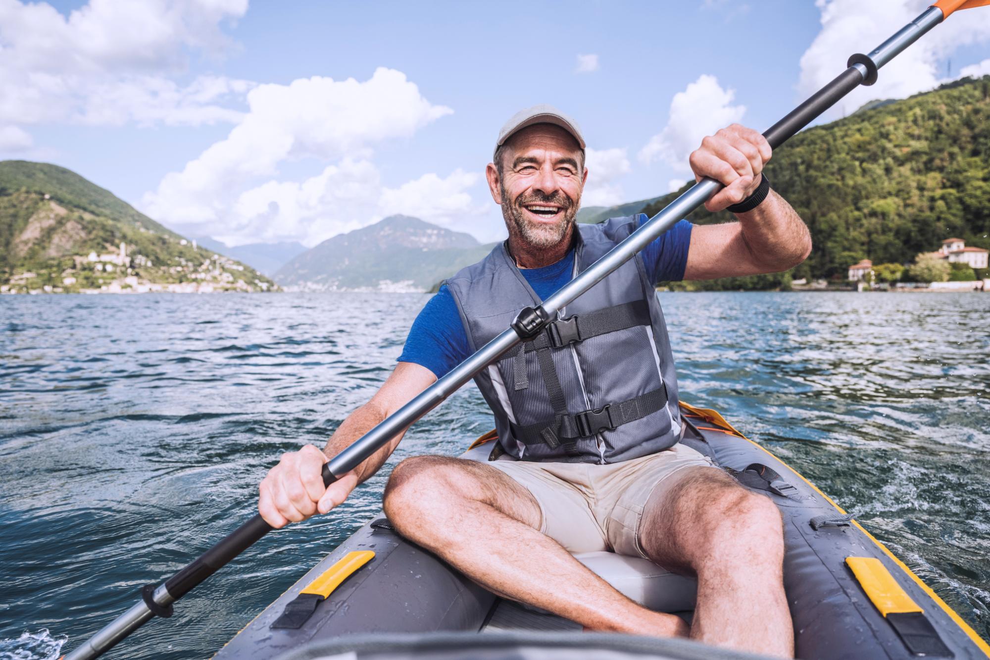 Cheerful mature man enjoying kayaking at lake