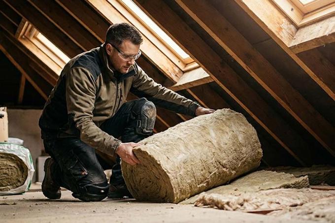 Un homme pose de l'isolant sous la toiture