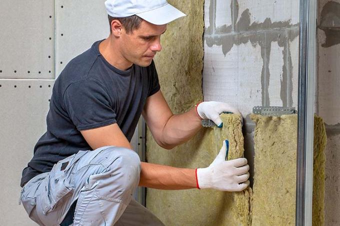 Un homme pose de l'isolant sous la toiture