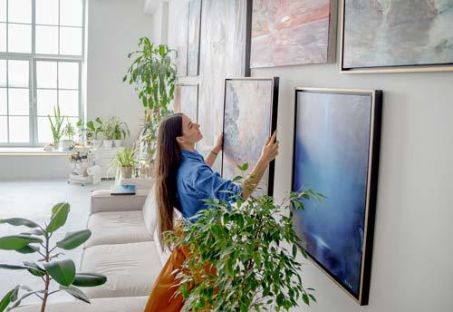 Une femme accroche une peinture dans une galerie